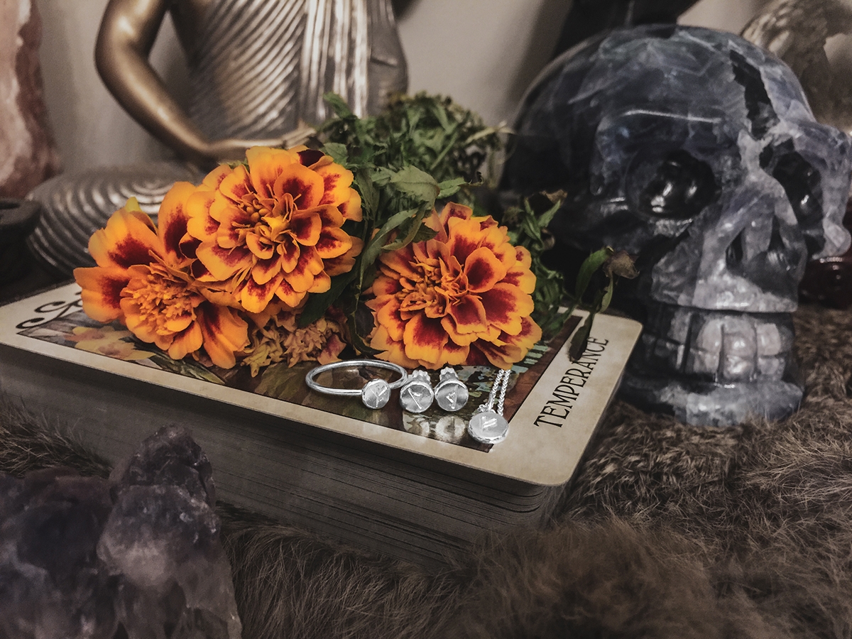 Sterling silver rune jewelry displayed on a stack of tarot cards.