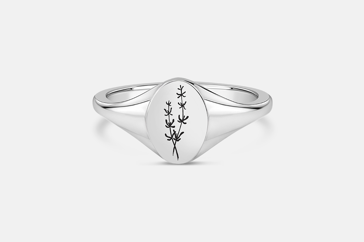 Sterling silver signet ring on a white background engraved with drawing of thyme plant.