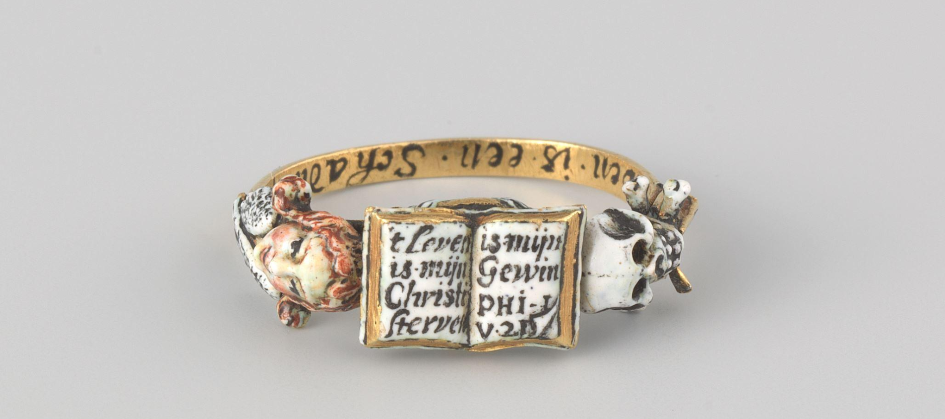 Memento Mori Ring, Anonymous, ca. 1640 - 1660 This gold ring is decorated with memento mori motifs. The Bible text in the open book ’t Leven is mijn Christi, Sterven is mijn Gewin’, (For me, to live is Christ and to die is gain.) The skull with hourglass and the angel reminded the wearer of the ring of the transience of earthly life. On the inside is an inscription: 'our life is a shadow on earth'.
