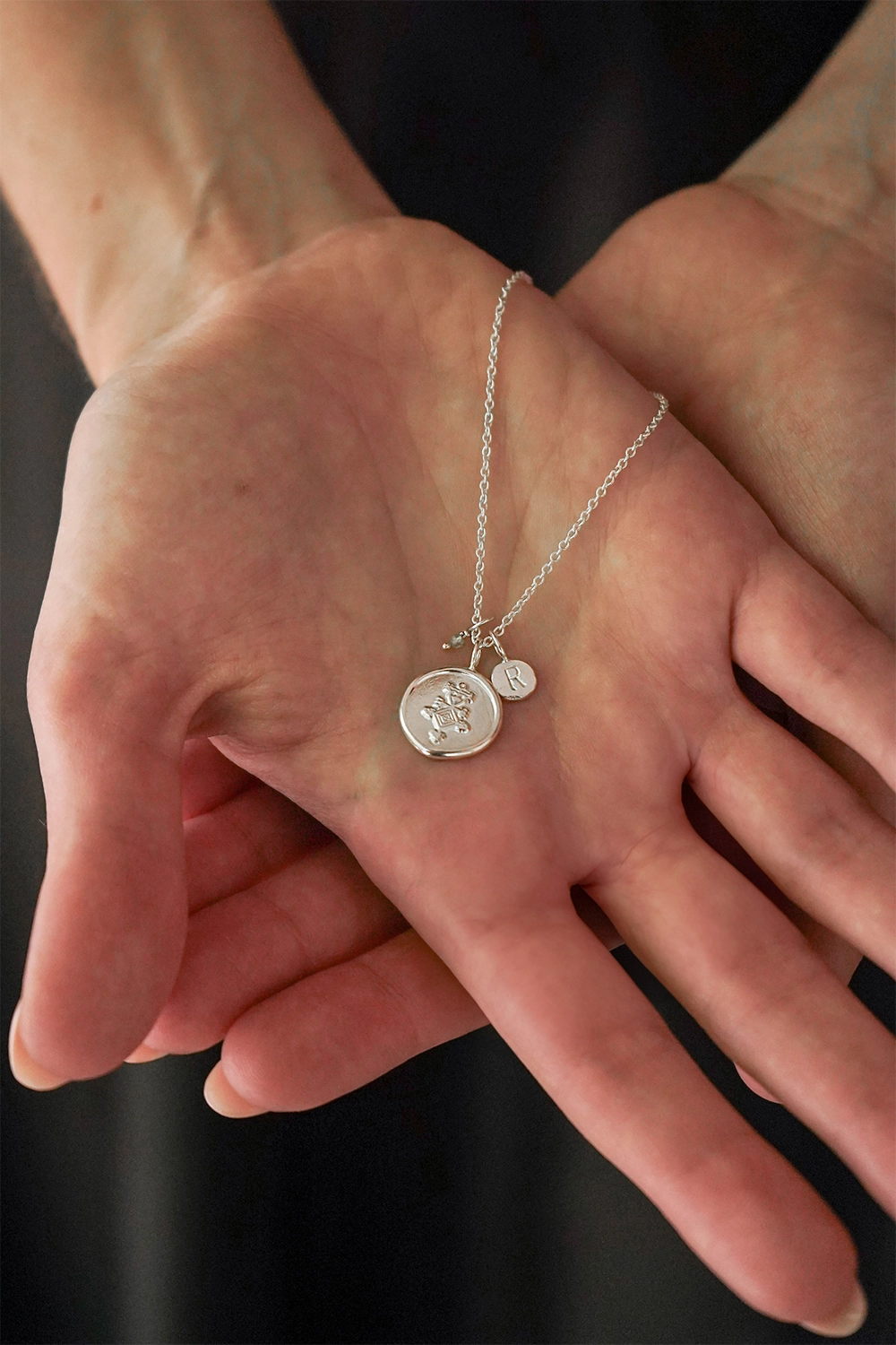 Nested hands holding a silver pendant for a bridesmaid gift.