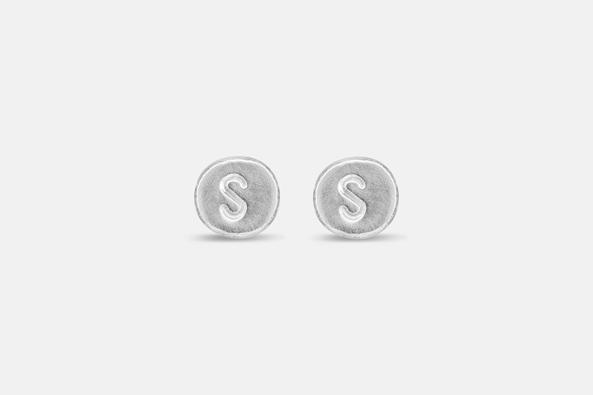 Round stamped silver letter earrings with the letter S.