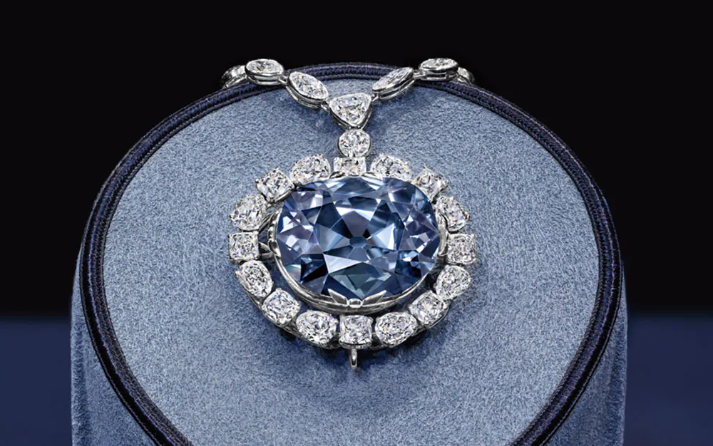 Photograph of the hope diamond necklace on a blue velvet stand.