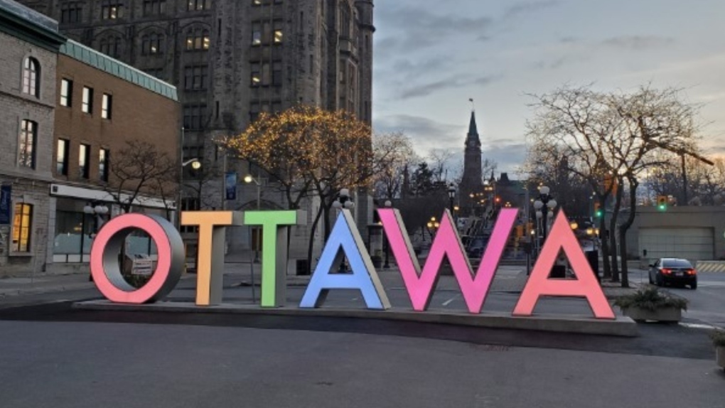 A picture of the Ottawa sign in the byward market lit up in rainbow colours.