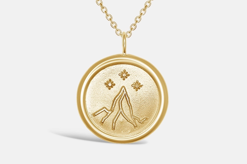 Gold pendant showing the night court insignia from the A Court of Thorns and Roses Series. A mountain peak at the centre of the pendant is topped by three small stars.